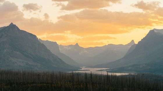 A sunset over a mountain range with a lake in the middle.